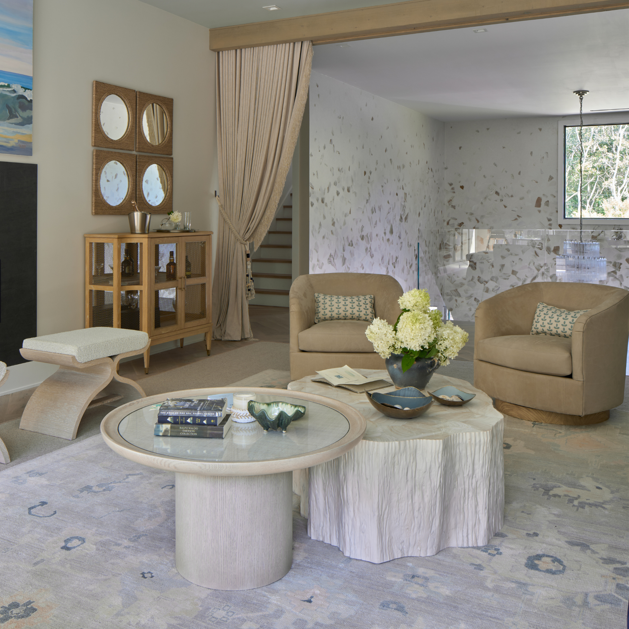 Living room with beige armchairs, a round coffee table, and decorative elements.