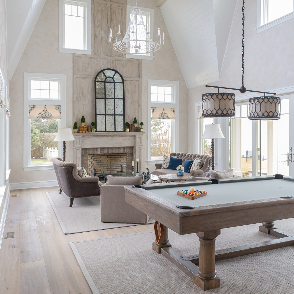 Living room with a pool table, fireplace, and large windows.