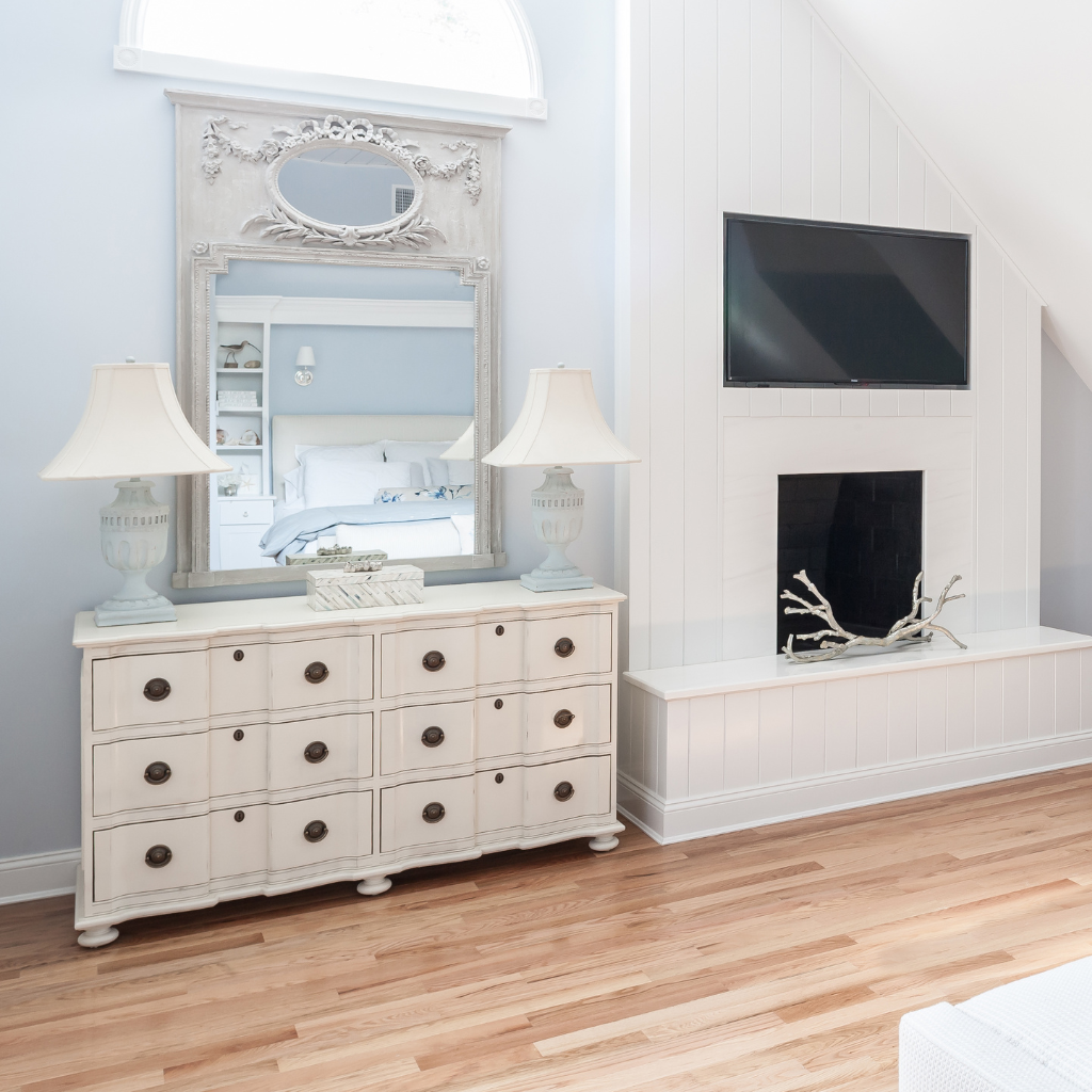 Living room with white dresser, mirror, and TV above fireplace.