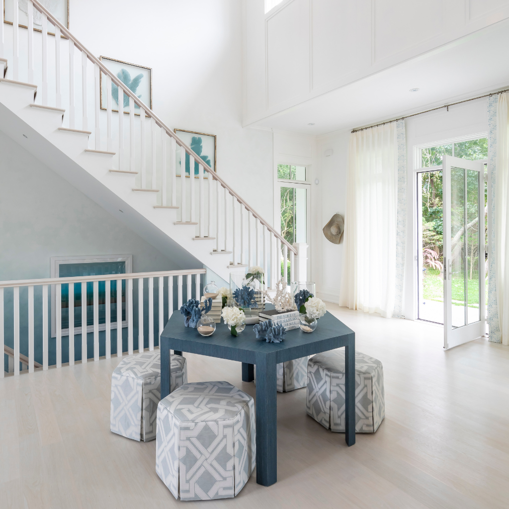 Modern interior with a blue dining table and patterned stools in a bright room.