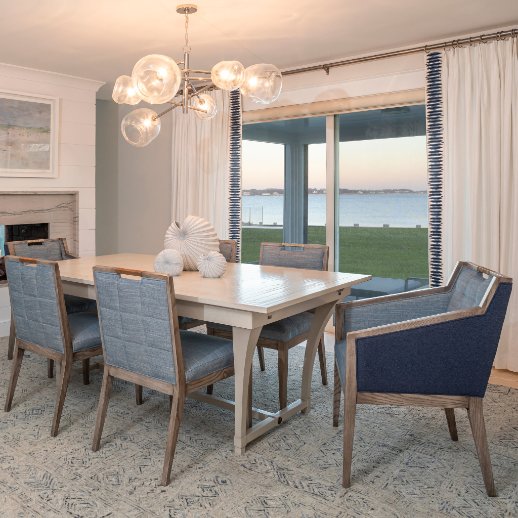 Dining room with a wooden table and chairs, large windows, and a chandelier.
