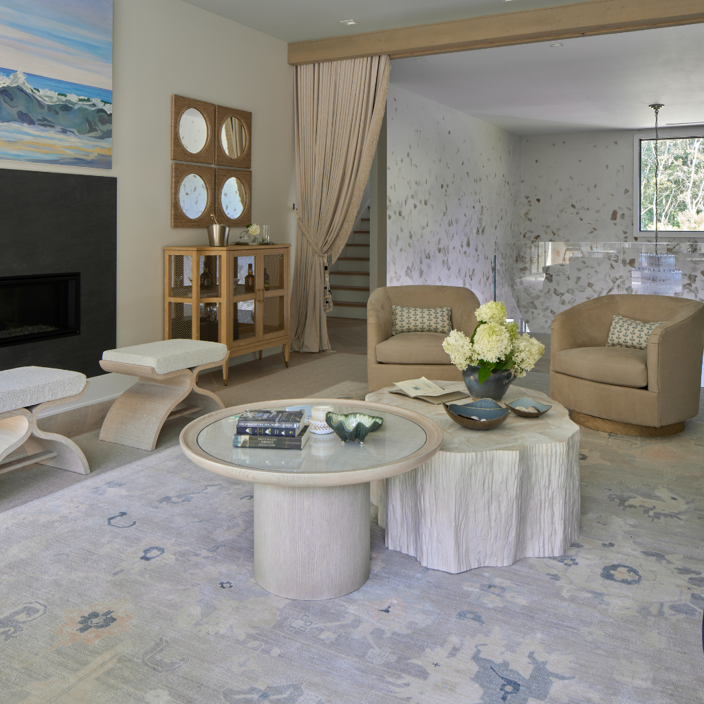 Modern living room with beige chairs, a glass coffee table, and decorative elements.