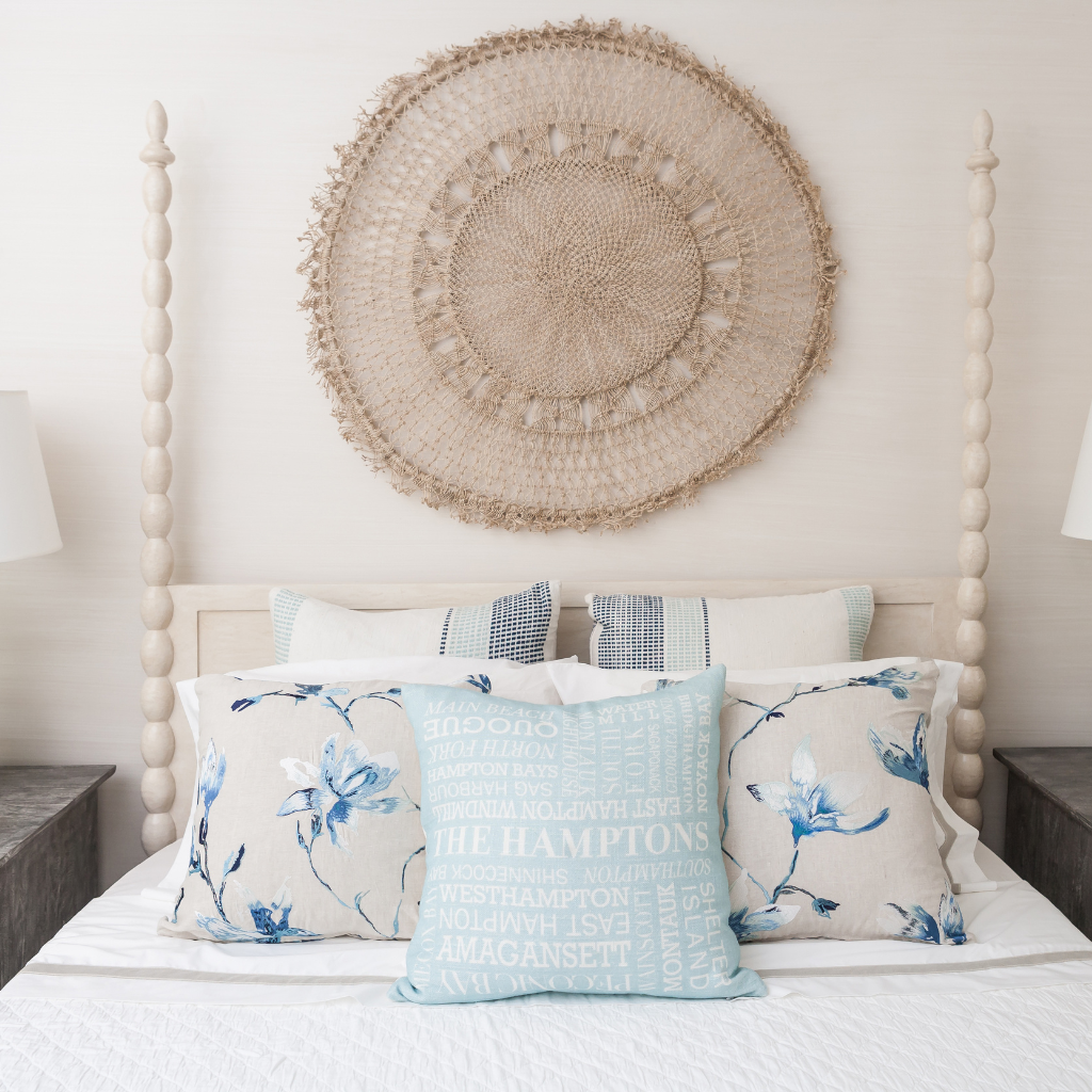 Bedroom with floral and text pillows on a bed, decorative wall hanging above.