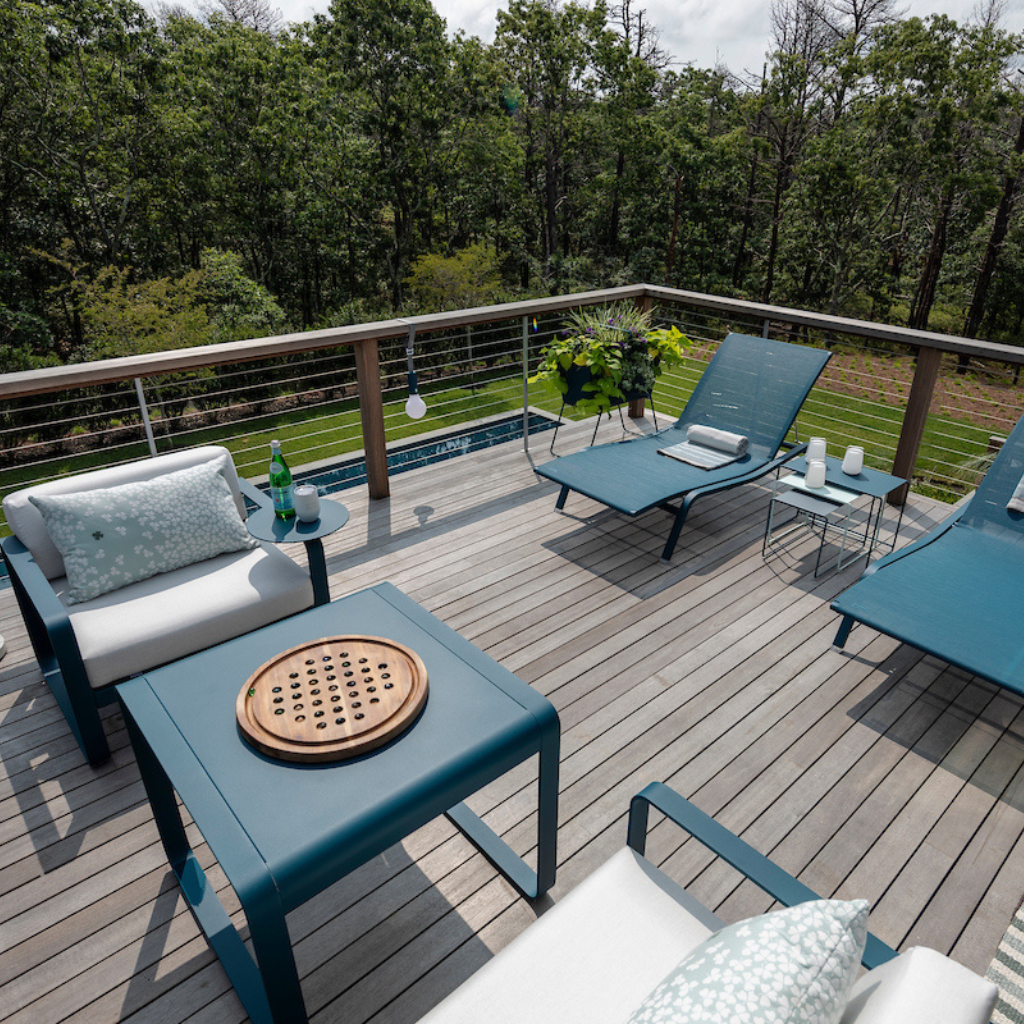 Outdoor deck with patio furniture, table, and view of trees