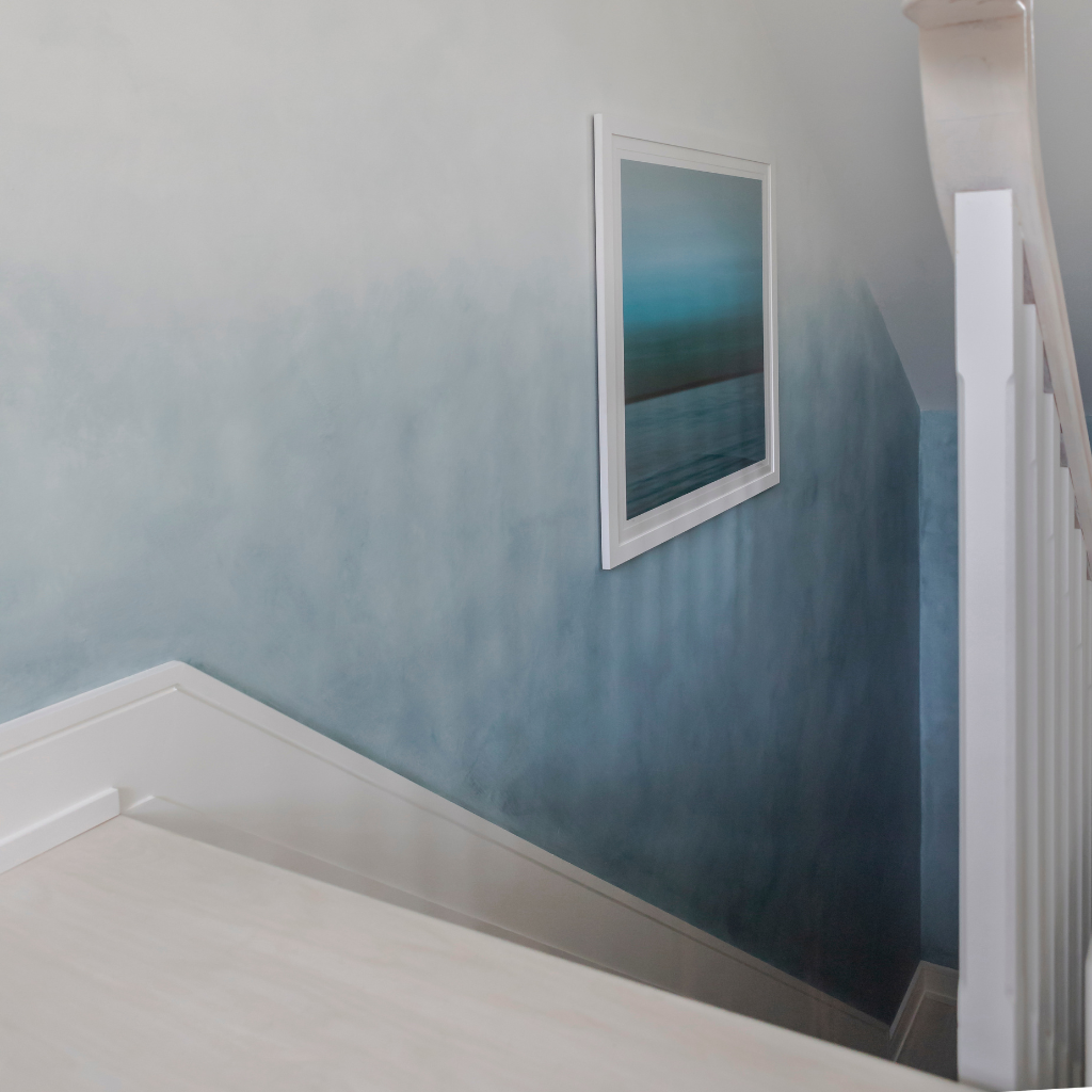 Stairwell with a blue gradient wall and framed artwork.