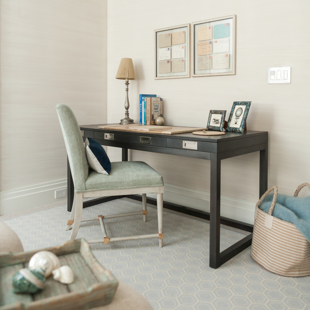 Home office with a desk, chair, and decorative items on a light gray tiled floor.