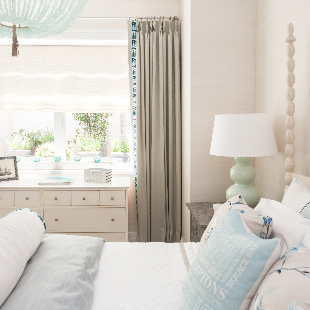 Neatly made bed with light blue pillows in a bright bedroom.