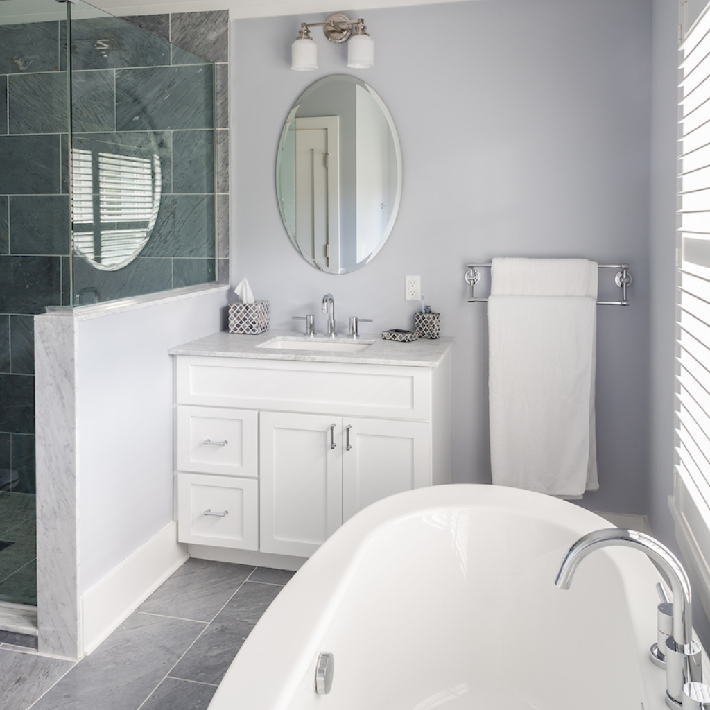 Bathroom with white vanity, round mirror, and bathtub.