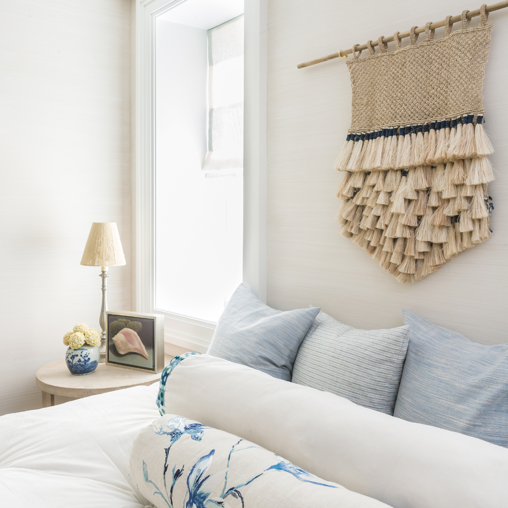 Cozy bedroom with a bed, lamp, and decorative wall hanging.