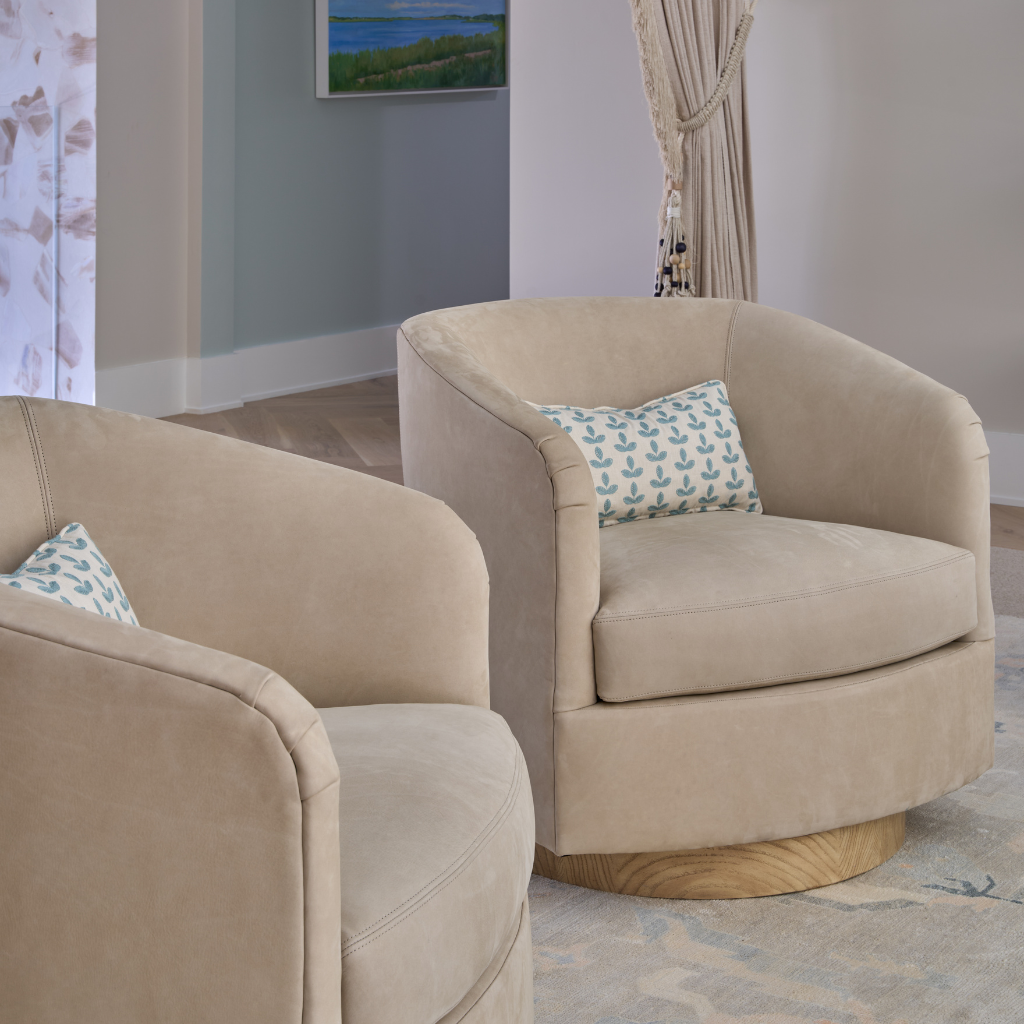 Two beige armchairs with patterned cushions in a room with a painting on the wall.