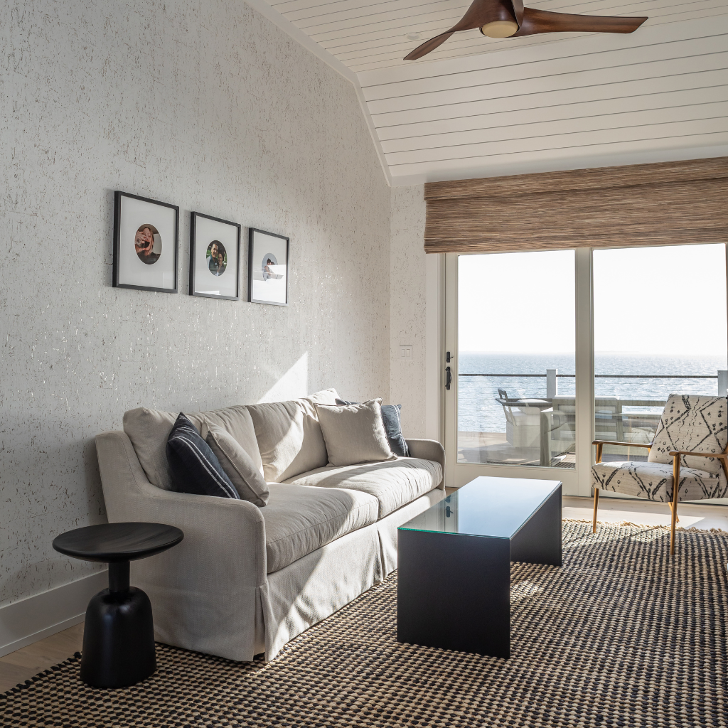 Modern living room with a gray sofa, coffee table, and view of the ocean.