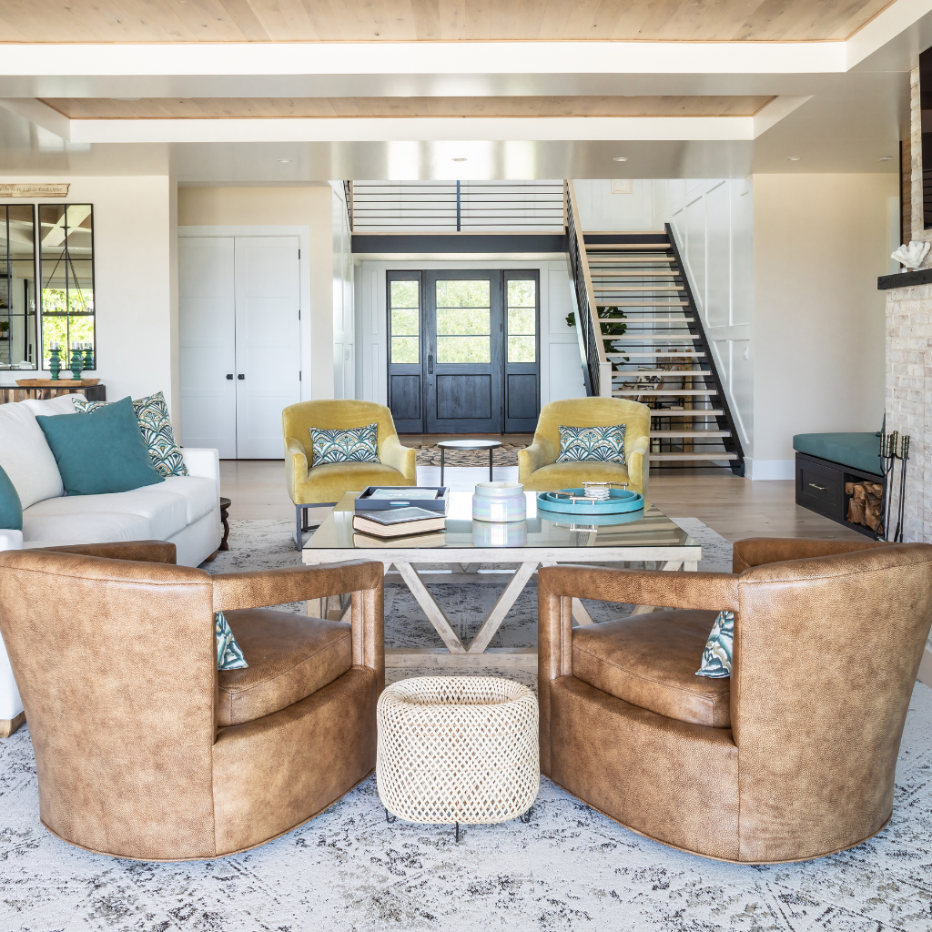 Modern living room with brown leather chairs, a glass coffee table, and decorative pillows.