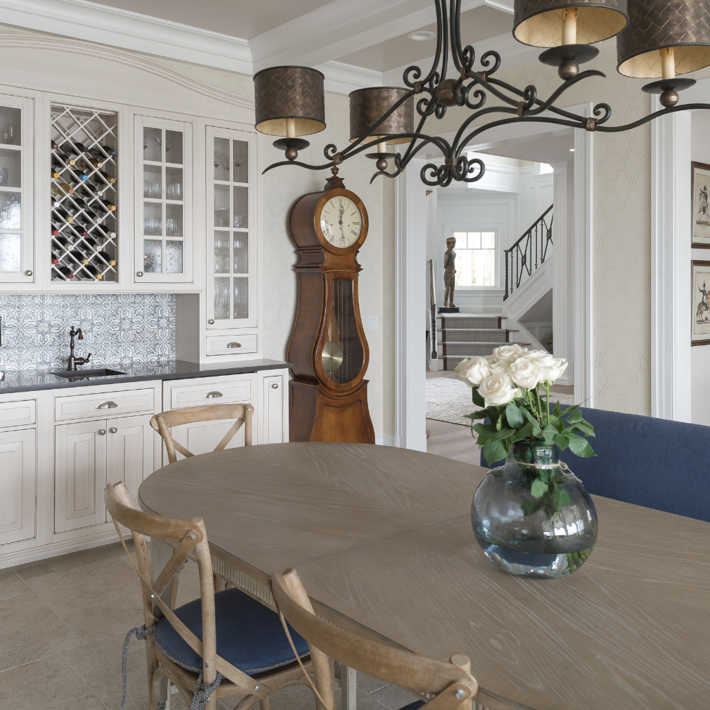 Dining room with wooden table, chairs, grandfather clock, and vase of flowers.