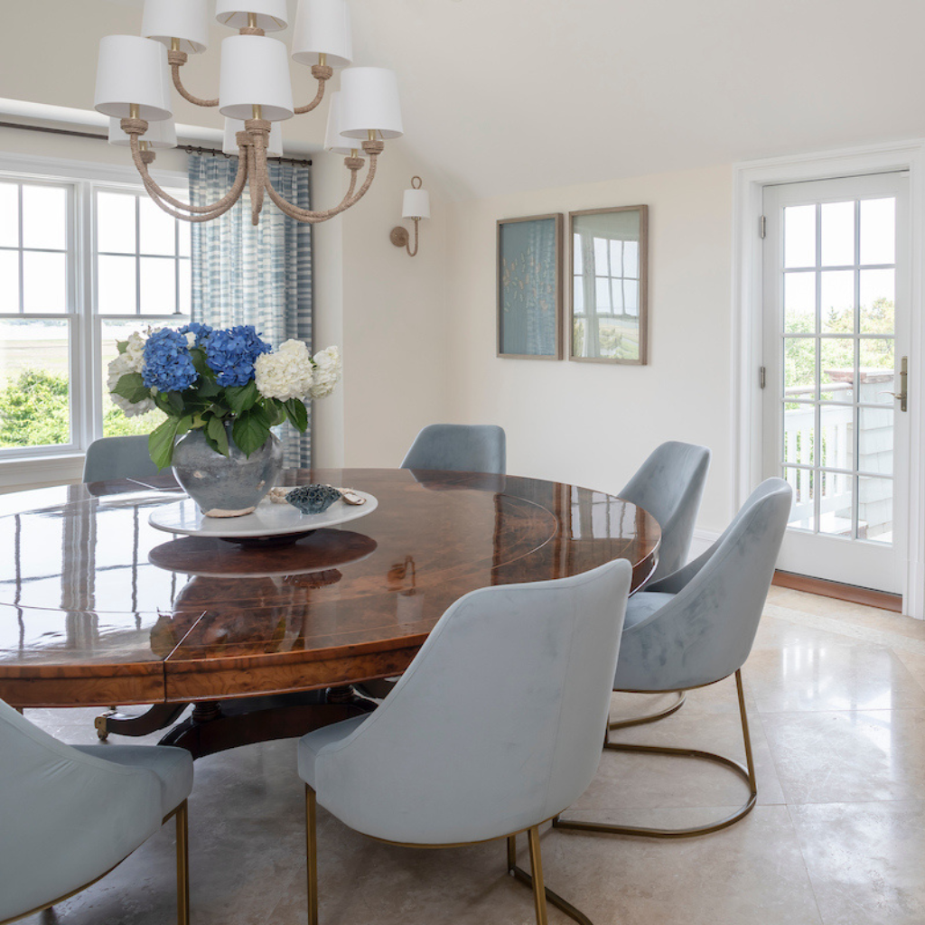 Dining room with a wooden table and light blue chairs, featuring a chandelier and floral arrangement.
