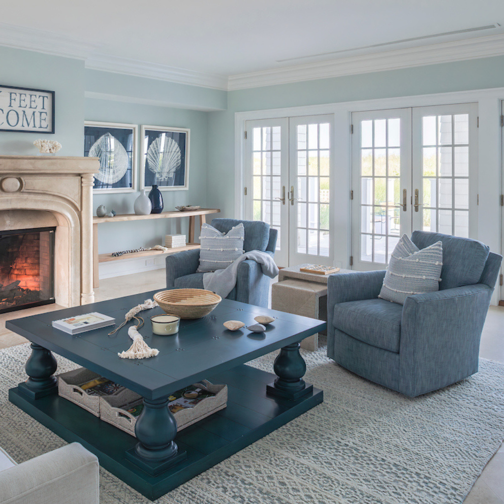 Living room with blue coffee table, gray armchairs, and large windows.