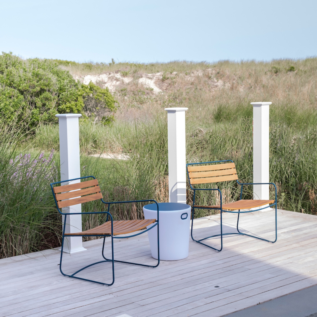 Two wooden chairs with metal frames on a wooden deck with a scenic background.