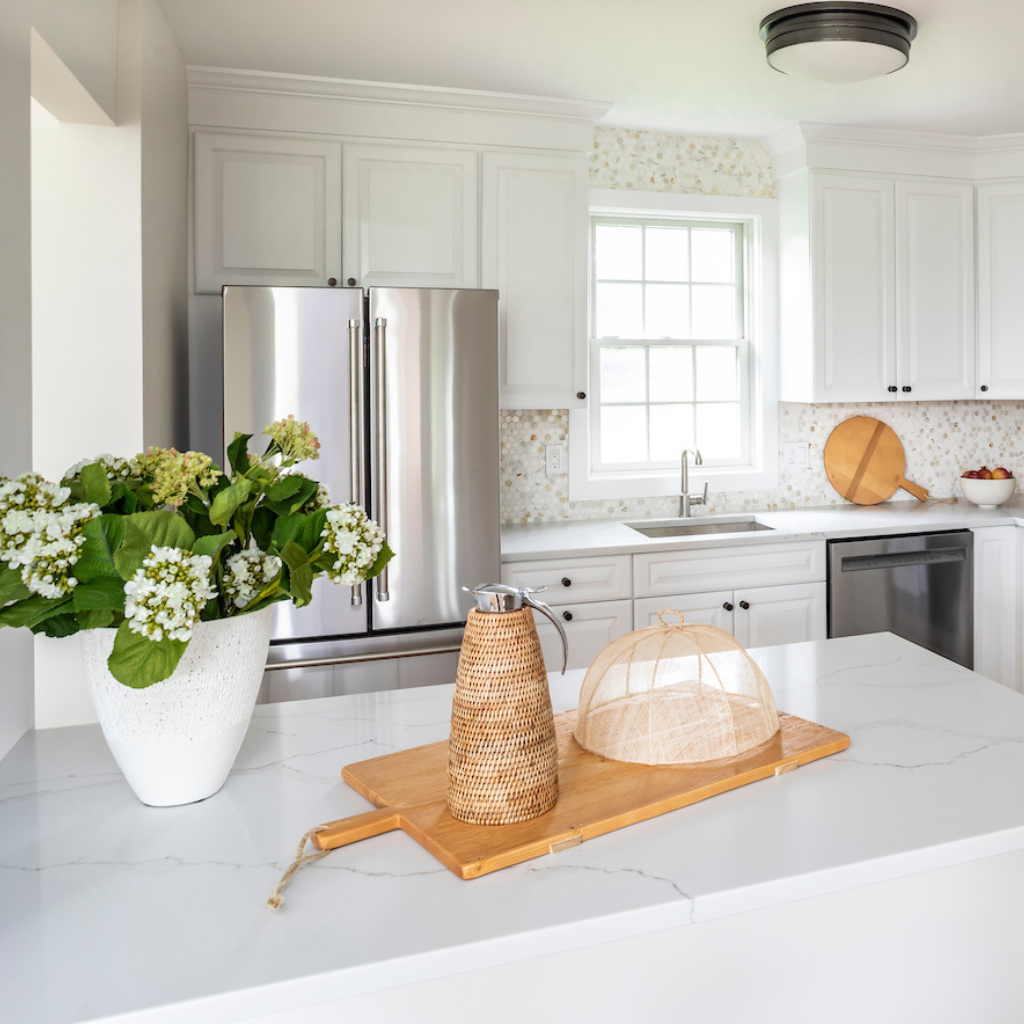 Modern kitchen with white countertops, stainless steel appliances, and decorative elements.