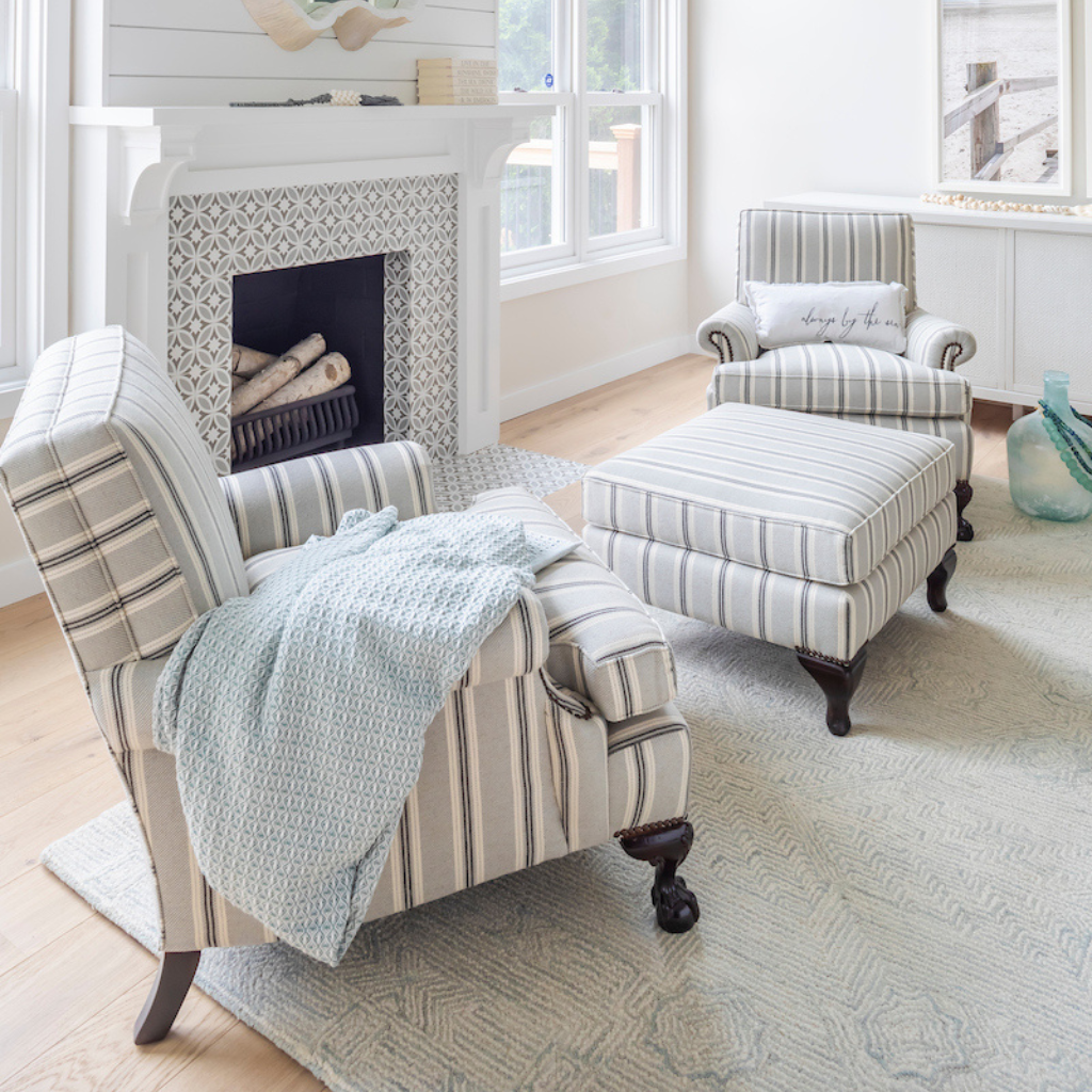 Living room with striped armchair, ottoman, and fireplace.