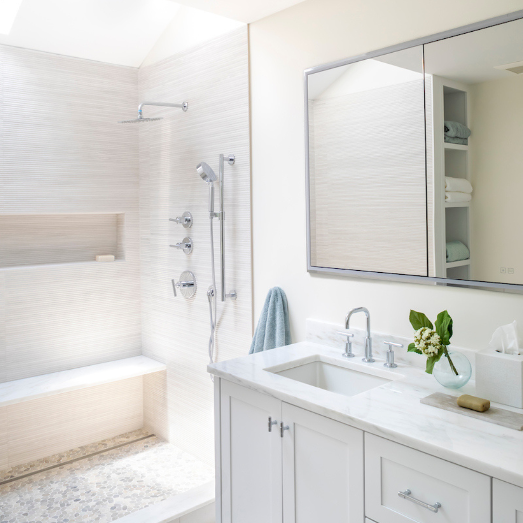 Modern bathroom with white vanity, sink, and shower area.