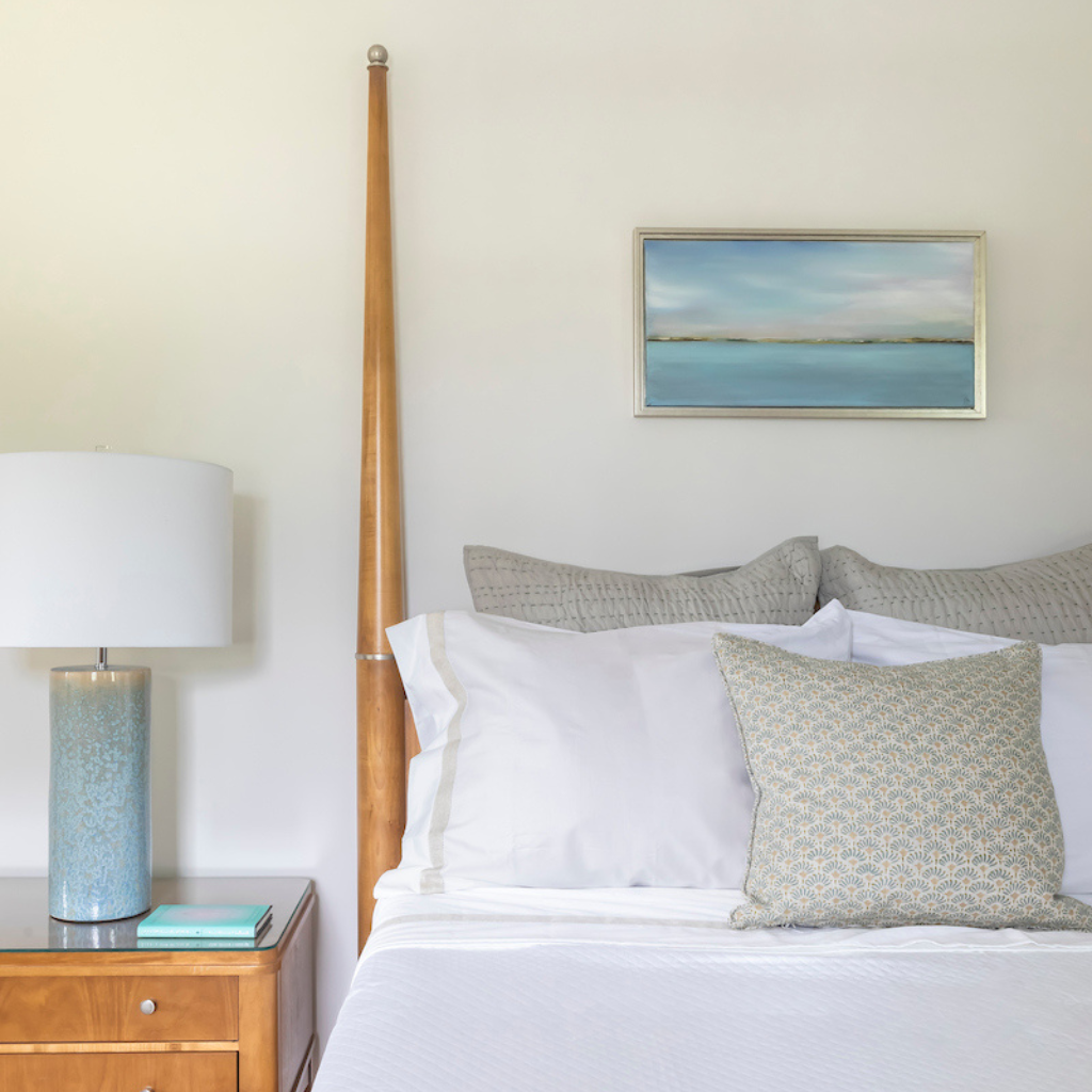 Bedroom with wooden headboard, white bedding, and a lamp on a nightstand.