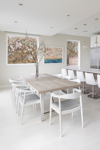 Modern dining area with a wooden table and white chairs in a bright room.