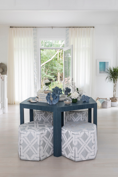 Modern dining area with a blue table and patterned stools in a bright room.