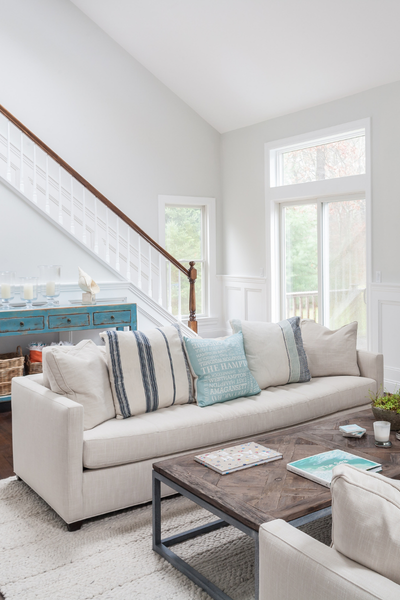 Living room with a beige sofa, wooden coffee table, and large windows.