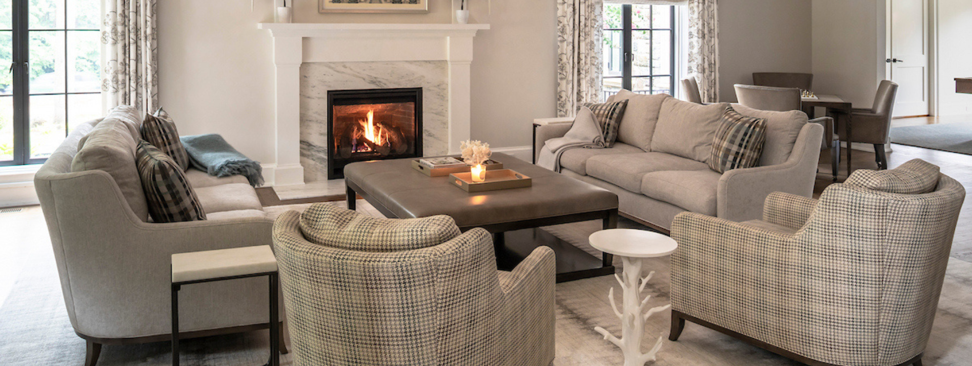 Living room with gray sofas, plaid armchairs, and a fireplace.