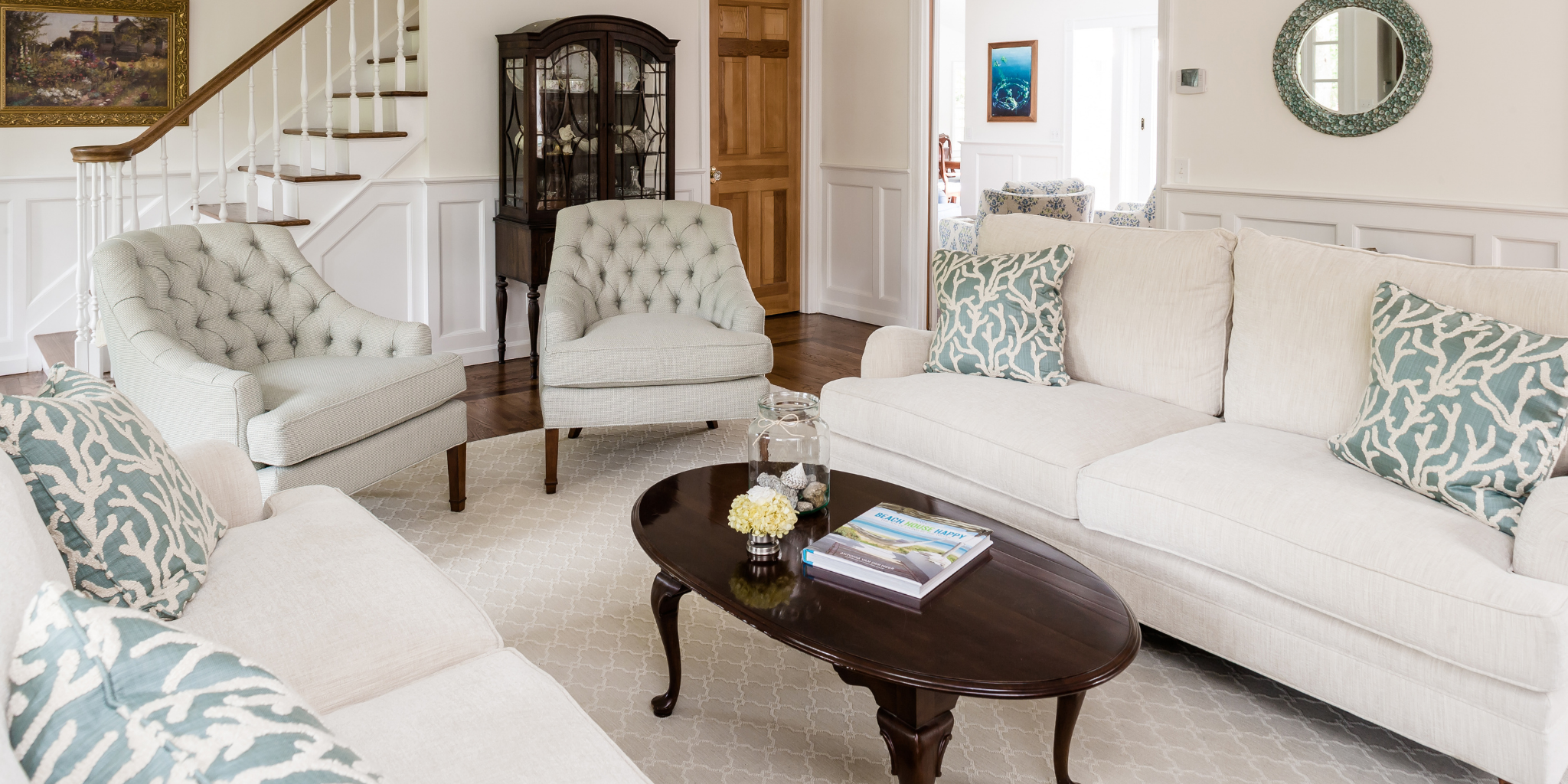 Living room with white sofas, patterned pillows, and a wooden coffee table.