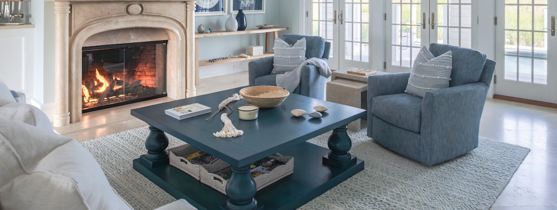 Living room with blue armchairs, coffee table, and fireplace.