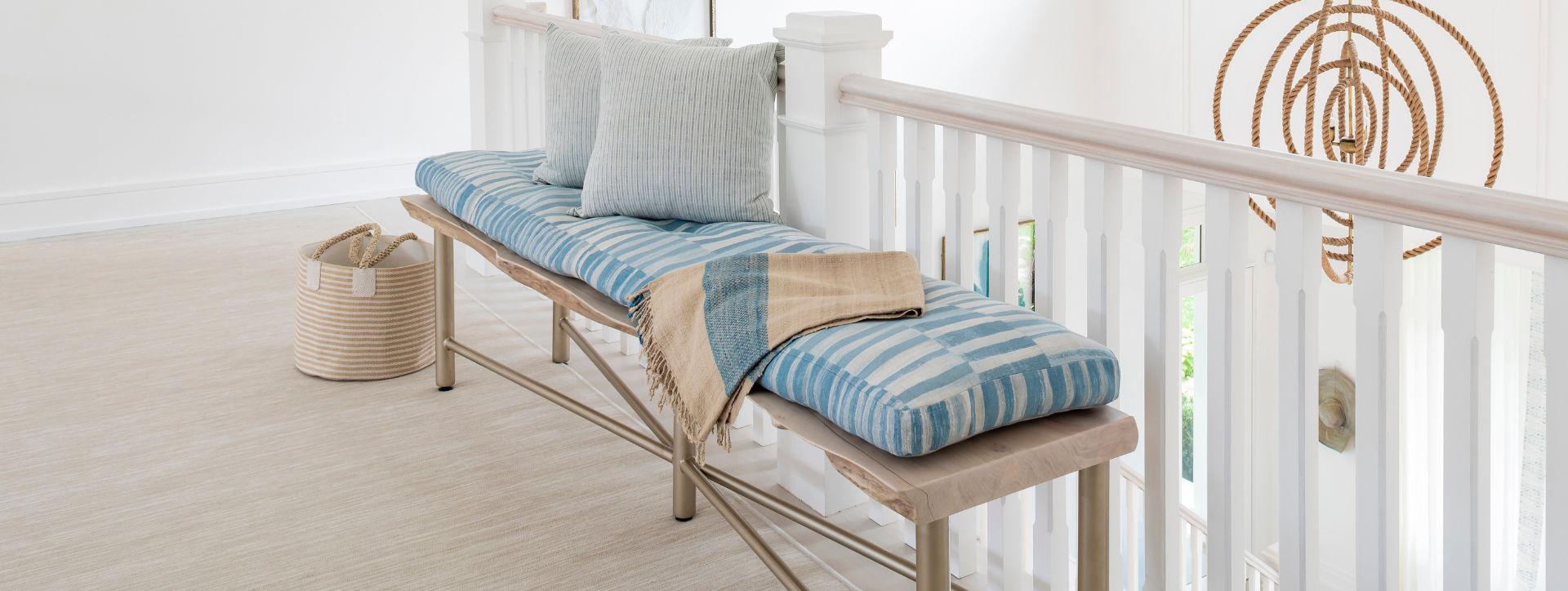Wooden bench with striped cushions and a woven basket on a light wooden floor.