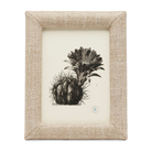 A framed botanical art print featuring a detailed black ink illustration of a cactus and succulent on an off-white background, enclosed in a textured beige woven frame.
